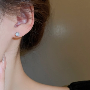Close-up of sparkling round cubic zirconia stud earring worn on earlobe in silver setting