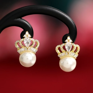 Close-up of elegant crown earrings with white pearls and sparkling zircon details