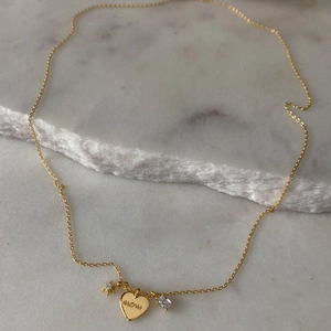 Gold Mom necklace with heart pendant, star charms and crystals on marble background