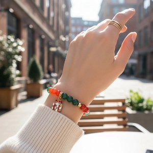 Christmas pearl bracelet with red and green beads and a small gift box pendant on wrist
