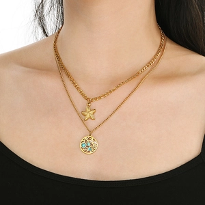 Détail d'un collier double rang en acier doré avec pendentifs étoile de mer et turquoise