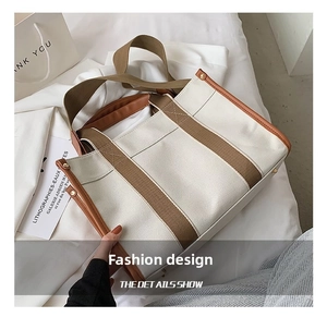 Close-up of canvas tote bag featuring brown leather trim and stylish webbing handles
