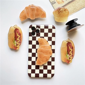 Flat lay of realistic 3D food-shaped phone grips with croissant and muffin designs