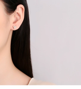Detailed close-up of a 925 silver bow stud earring with pearl on model's ear