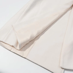 Detail of beige wool coat hem showing high-quality fabric texture and smooth lining finish