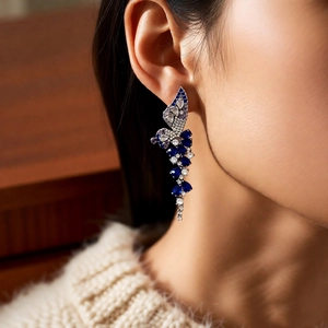 Detail of wing earrings with blue sapphire tassels and clear crystals on model