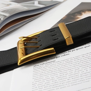 Close-up of black elastic waist belt with a golden buckle on a fashion magazine background