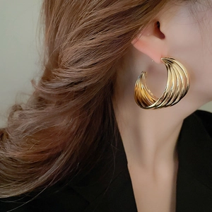 Close-up of golden multi-layer C-shaped hoop earrings on a model in black blazer