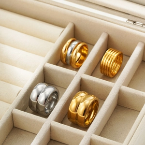 Close-up of gold and silver double-layered textured rings in a beige velvet jewelry box