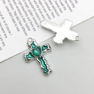 Front and back detail of silver cross pendant with green heart gemstone and enamel