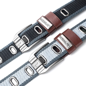 Two casual canvas belts with metal buckles and leather loops on white background