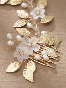 Macro shot of gold leaf bridal hair comb with white flowers and pearls detail