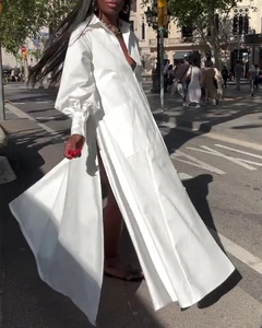 Vue latérale dynamique d'une robe chemise maxi blanche à fente haute et manches bouffantes
