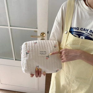Detail of white quilted cotton bag featuring delicate tulip embroidery and zip closure