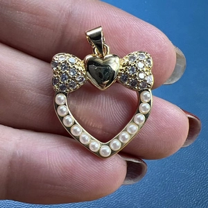 Golden heart pendant with bow knot, clear zircons and white pearl outline details