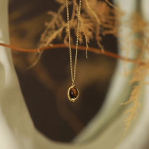 Artistic detail of vintage gold chain necklace with brown tiger eye stone pendant