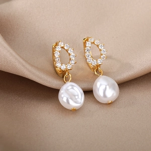 Detail of baroque pearl drop earrings with zircon inlay on luxury champagne silk fabric