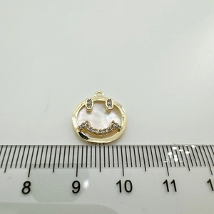 Macro shot of 18K gold-plated shell smiley pendant with cubic zirconia eyes and 1.3cm ruler