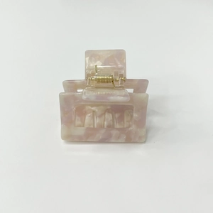 Detailed macro view of small pink marble square hair claw clip with golden metal spring