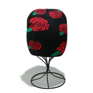 Close-up of knit beanie featuring vibrant red rose jacquard and soft black fabric texture