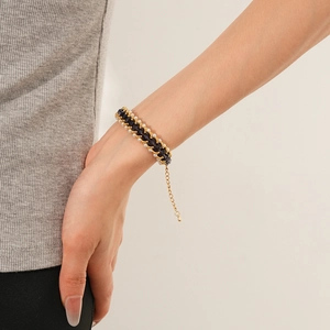 Close-up of retro pearl braided bracelet with black beads and gold adjustable chain