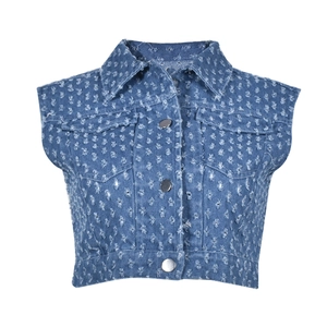 Detail view of distressed blue denim vest featuring ripped holes and metal button closure