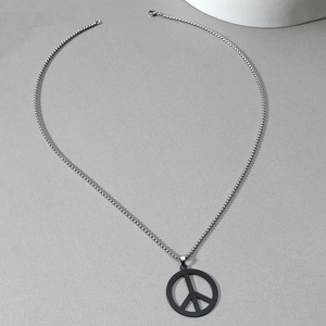 Top-down view of a minimalist silver chain with a matte black peace sign pendant detail