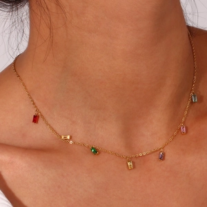 Close-up of elegant gold chain necklace with colorful square zircon pendants on neck