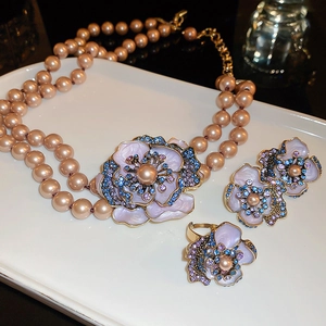 Macro detail of vintage floral jewelry set with pink pearls and purple enamel petals