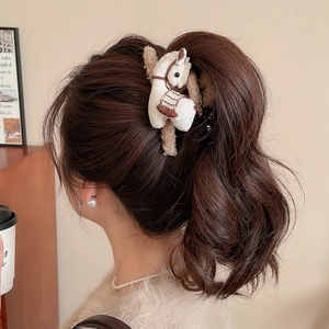 Detail of cream plush pony hair claw clip styled on brunette wavy hair for daily wear