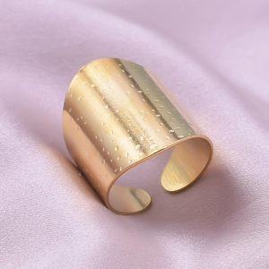 Makro-Detail des goldenen offenen Rings mit gehämmerter Textur auf Seidenhintergrund