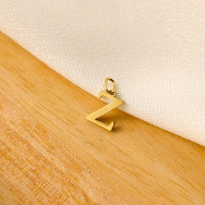 Macro shot of a minimalist gold capital letter Z pendant on a natural wood surface