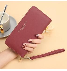 Deep burgundy cross-grain faux leather long wallet held by a model with golden zipper