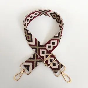 Detail of adjustable woven canvas strap with diamond patterns and golden metal snap hooks