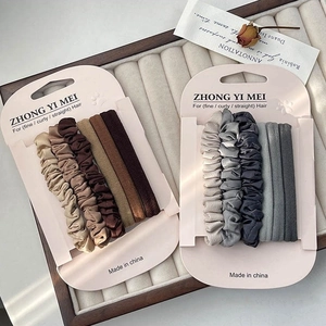 Macaron-Haargummi-Set in Braun und Grau auf einem Samttablett, hochelastisch
