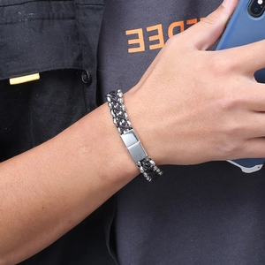 Détail du bracelet tressé en cuir noir et acier inoxydable porté sur le poignet