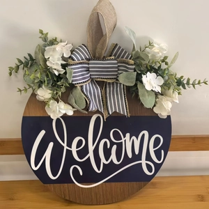 Round wooden welcome door sign with artificial white flowers and black-white striped bow