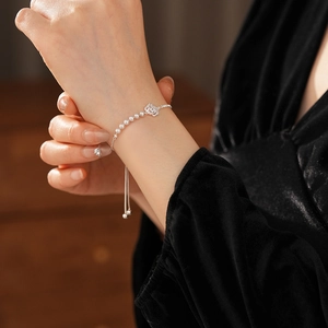 Détail du bracelet réglable en perles et fleurs de zircon porté au poignet d'une femme