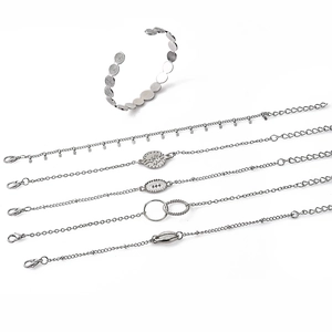 Detail of silver alloy jewelry set with crescent, tree of life, and conch shell charms