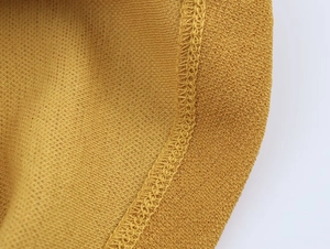 Dettaglio ravvicinato del tessuto a maglia giallo senape con cucitura overlock di qualità