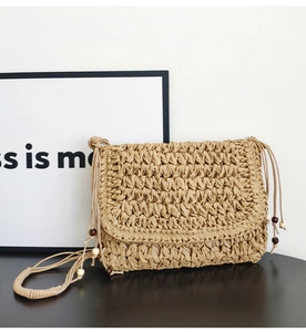 Detail of handmade straw crossbody bag with paper rope weave and wooden bead charm