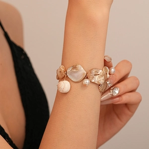 Close-up of ocean-style bracelet with natural shells, faux pearls and conch charms