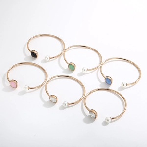 Rose gold open cuff bracelet with pearls and colorful square-cut crystals set on a white surface