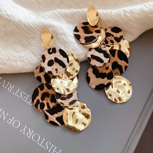 Détail de boucles d'oreilles pendantes avec disques léopard et métal doré martelé