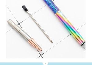 Disassembled view showing metallic rainbow pen barrel with blue glitter oil and core