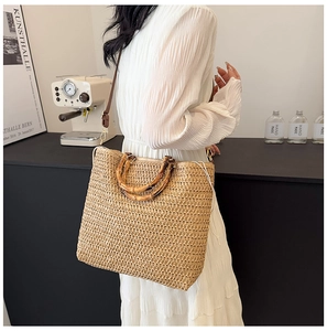 Detailed shot of large woven straw tote bag with bamboo handle and leather strap detail