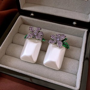Macro detail of silver flower earrings with purple rhinestones and white pearl drops