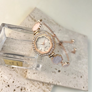 Close-up of rose gold flower watch with crystal bezel and pink clover charms on band