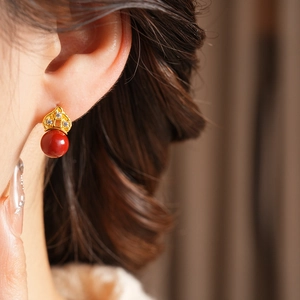 Macro view of gold flower earring with crystal studs and smooth red round bead