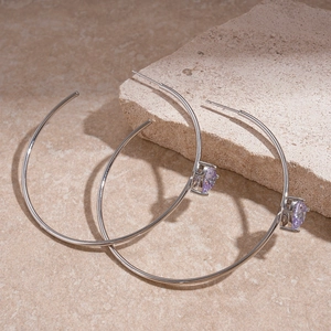 Detailed view of silver hoop earrings featuring a lavender stone on a textured stone base